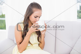 Calm young brunette drinking from a mug