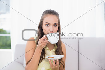 Serious young brunette drinking from a cup