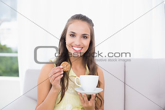 Smiling pretty brunette holding a cookie