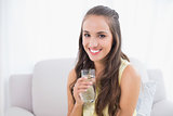 Smiling young brunette holding glass of water