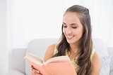 Smiling young brunette reading a book