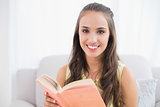 Smiling young brunette holding a book