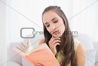 Thoughtful young brunette reading a book