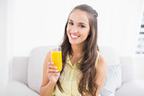 Smiling pretty brunette holding glass of orange juice