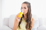 Calm young brunette drinking glass of orange juice