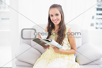 Smiling pretty brunette holding a magazine