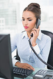 Serious brunette businesswoman phoning