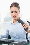 Angry brunette businesswoman hanging up the phone