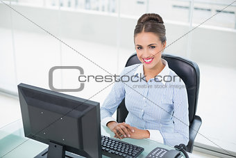 Smiling brunette businesswoman sitting at her desk