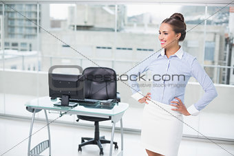Happy brunette businesswoman standing hands on hips