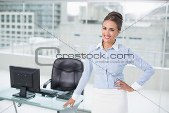 Cheerful brunette businesswoman standing hand on hips