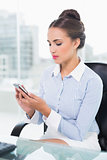 Calm brunette businesswoman touching smartphone