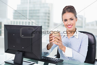 Smiling brunette businesswoman holding disposable cup