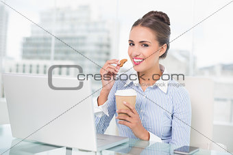 Smiling brunette businesswoman holding cookie