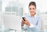 Smiling brunette businesswoman holding smartphone