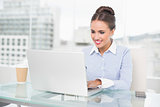 Smiling brunette businesswoman typing on laptop