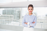 Content brunette businesswoman standing with arms crossed