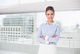 Smiling brunette businesswoman standing with arms crossed