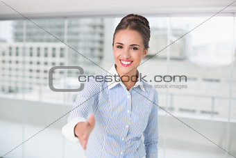 Cheerful brunette businesswoman standing for hand shake