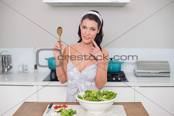Thoughtful pretty brunette holding wooden spoon