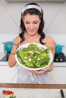 Smiling pretty brunette showing healthy salad