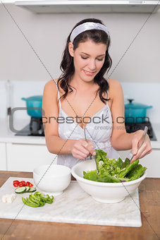 Happy pretty brunette mixing healthy salad