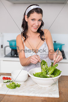 Cheerful pretty brunette mixing healthy salad