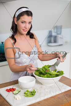 Smiling cute brunette mixing healthy salad