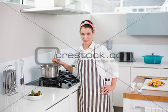 Serious pretty woman with apron cooking