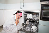 Worried charming woman sitting next to dish washer