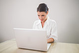 Focused charming businesswoman typing on laptop