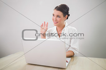 Waving charming businesswoman using laptop
