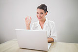 Waving gorgeous businesswoman using laptop