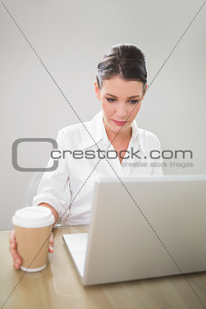 Pensive gorgeous businesswoman working on laptop