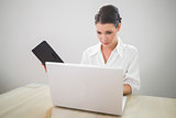 Focused businesswoman working on laptop holding datebook