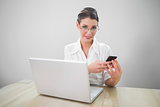 Cheerful businesswoman with classy glasses texting