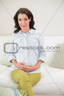 Peaceful pregnant brown haired woman holding her belly