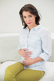 Relaxed pregnant brown haired woman holding her belly