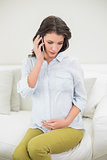 Peaceful pregnant brown haired woman making a phone call