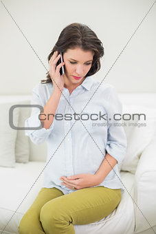 Peaceful pregnant brown haired woman making a phone call