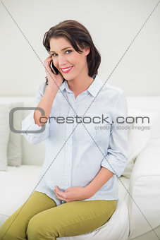 Smiling pregnant brown haired woman making a phone call