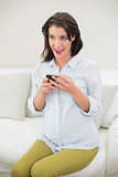Delighted pregnant brown haired woman using her mobile phone