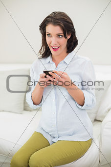 Delighted pregnant brown haired woman using her mobile phone