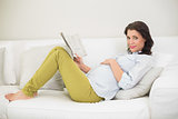 Relaxed pregnant brown haired woman reading a newspaper