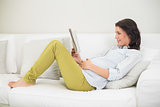 Peaceful pregnant brown haired woman reading a newspaper