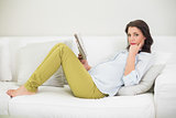 Pensive pregnant brown haired woman reading a newspaper
