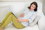 Charming pregnant brown haired woman using a tablet pc