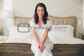 Pleased pretty brown hair woman sitting on a bed