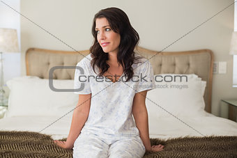 Pensive pretty brown hair woman sitting on a bed