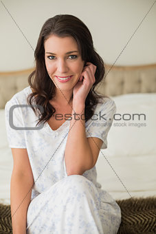 Smiling pretty brown haired woman sitting on a bed